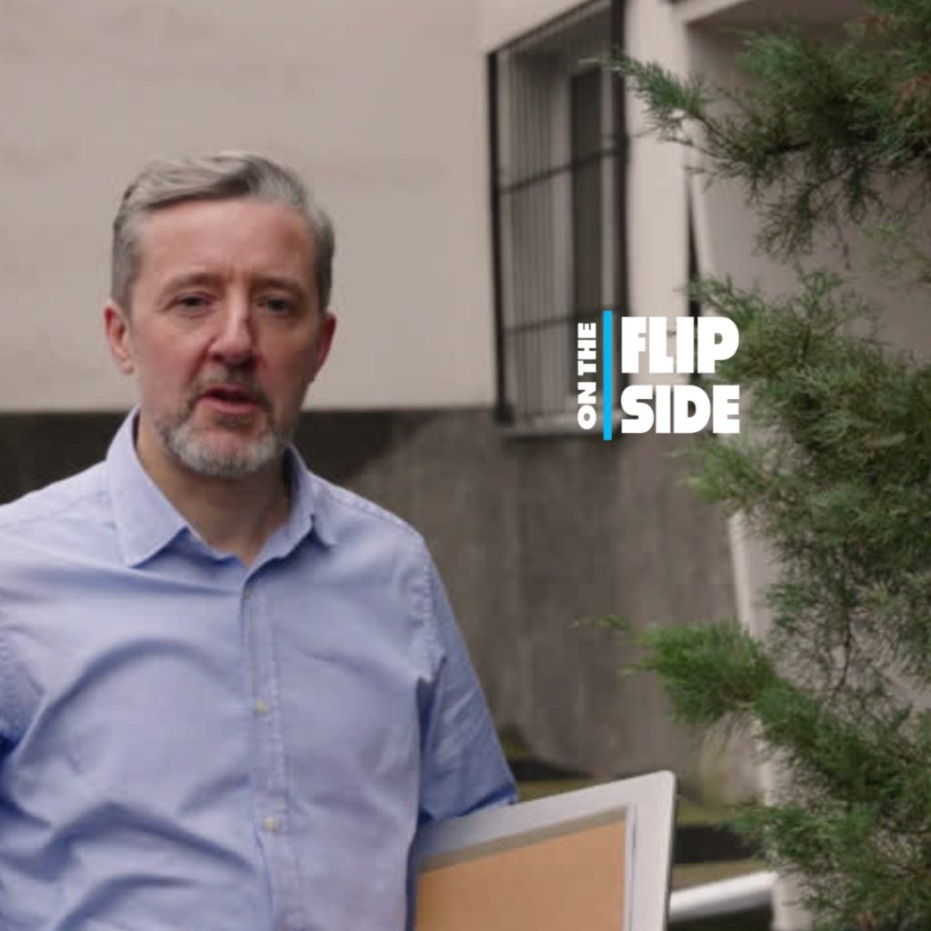 A man on property with a tablet and notebook with the "on the flip side" superimposed