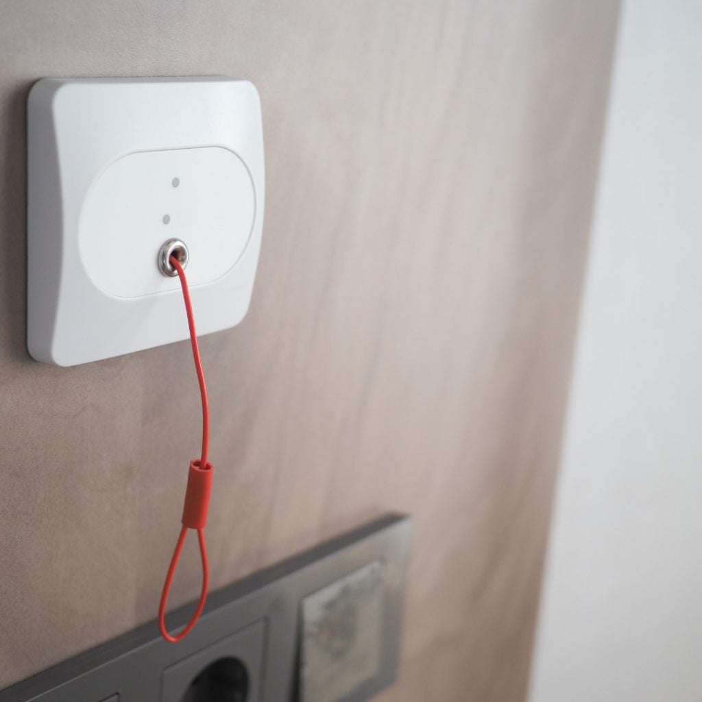 Red emergency pull cord attached to a wall-mounted call system in an apartment.