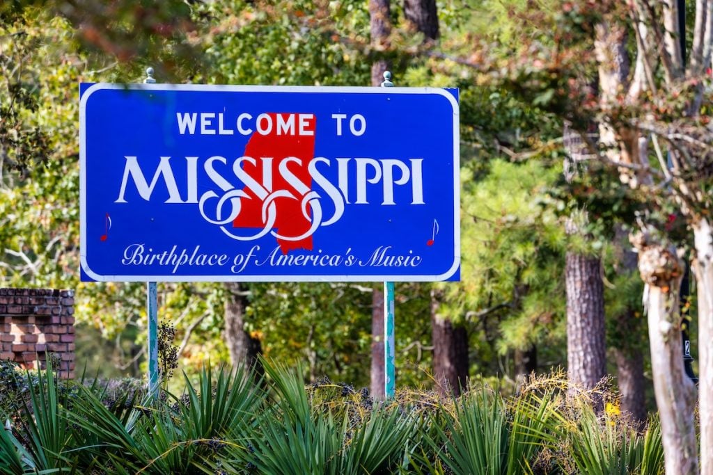 Welcome to Mississippi roadside sign surrounded by trees and greenery.