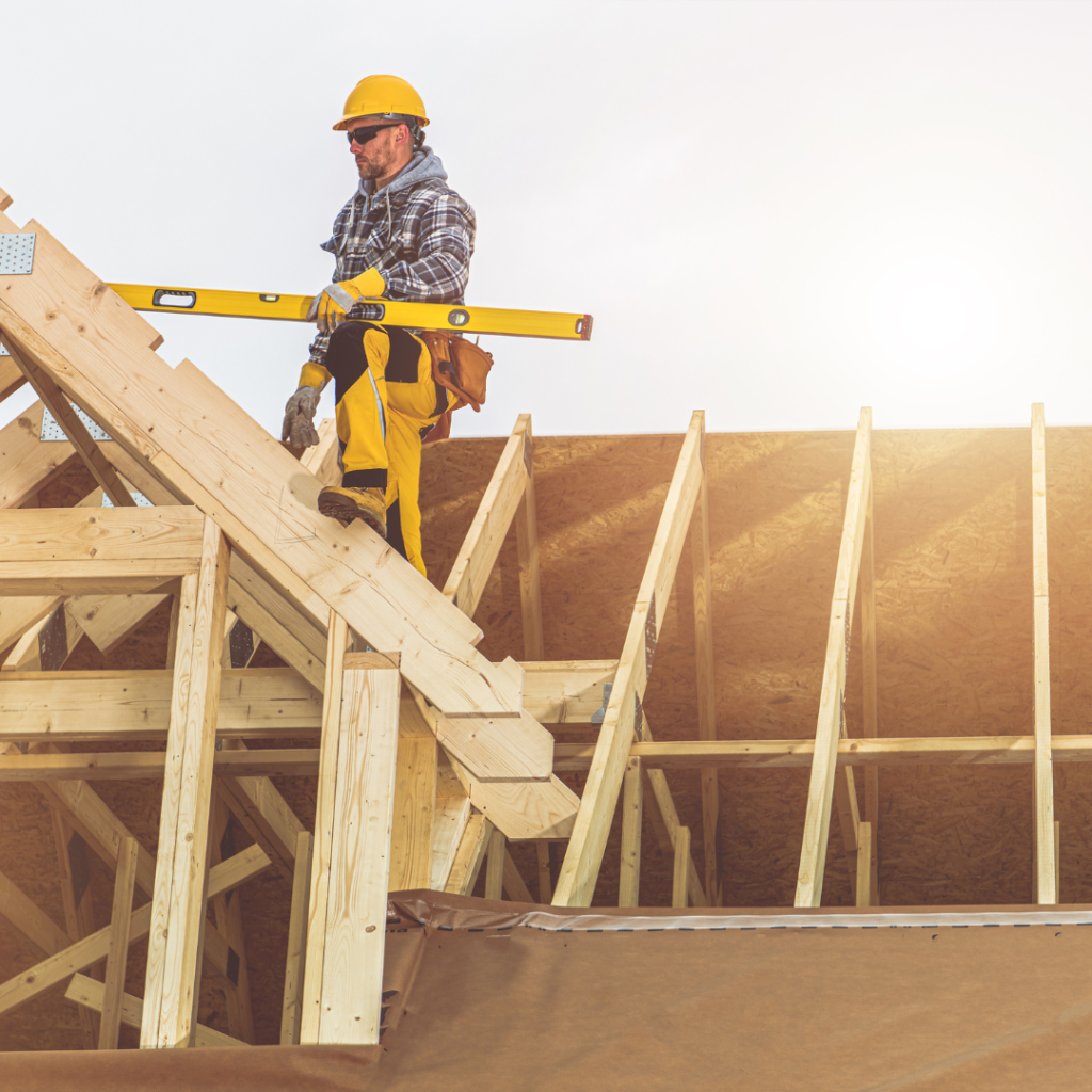 A construction work standing on top of a framed roof