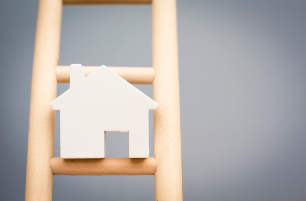 Model Houses On Rung Of Wooden Property Ladder