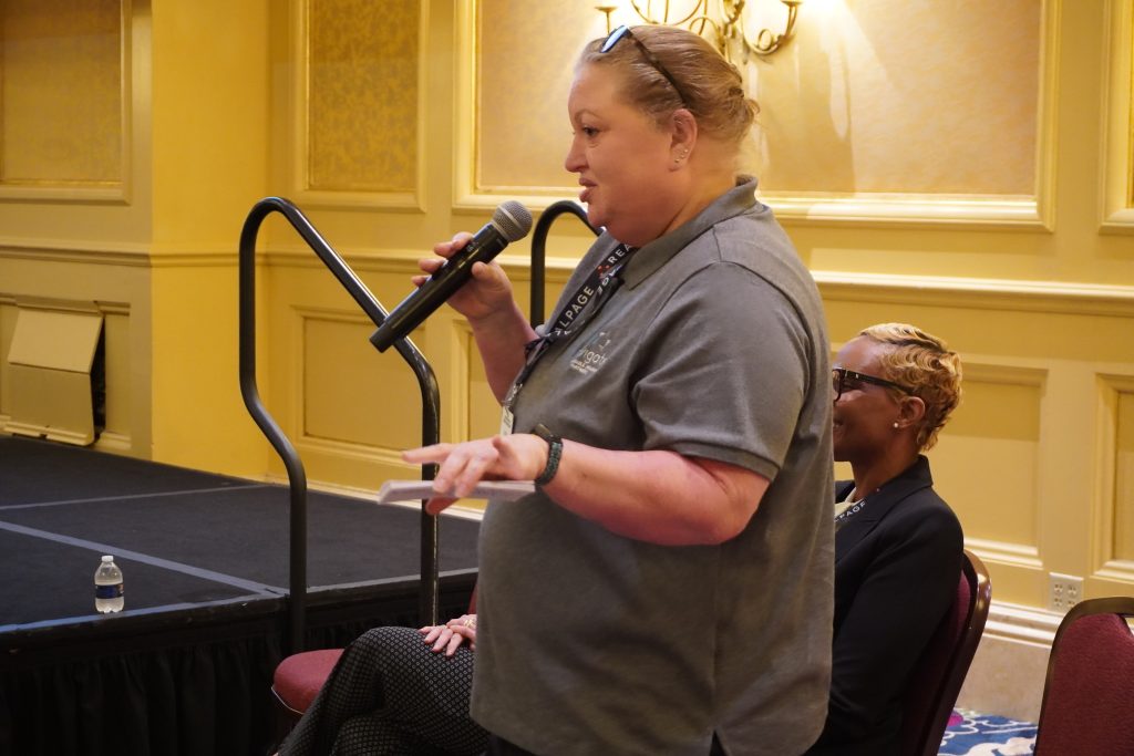 Navigate team member speaks into a microphone during a conference session.