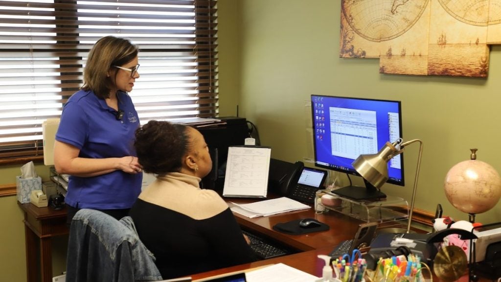 Navigate staff training a housing staffer in an office.