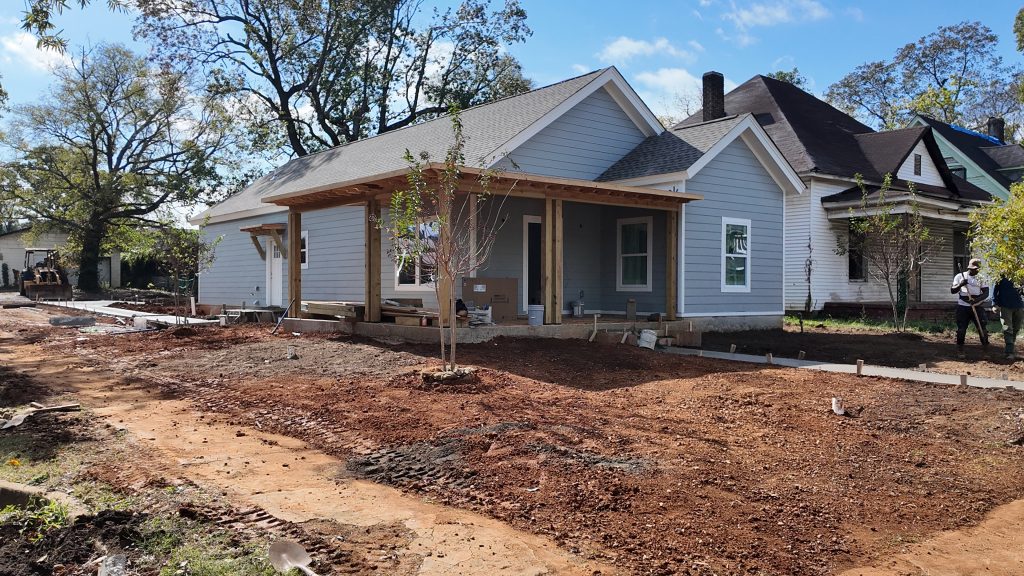 An almost finished gray home with porch in Woodlawn Neighborhood. There is no landscaping., Woodlawn United Homes