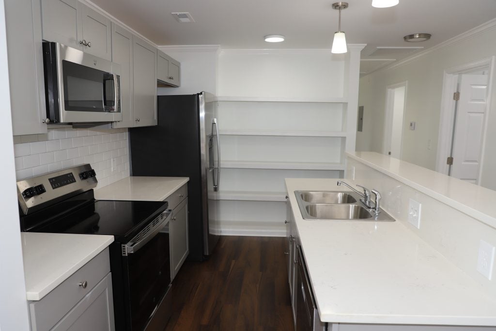A modern kitchen update with white counters, stainless steel sink and appliances
