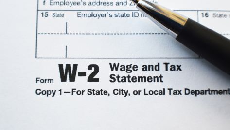 Close-up of a W-2 Wage and Tax Statement form with a pen resting on the document.