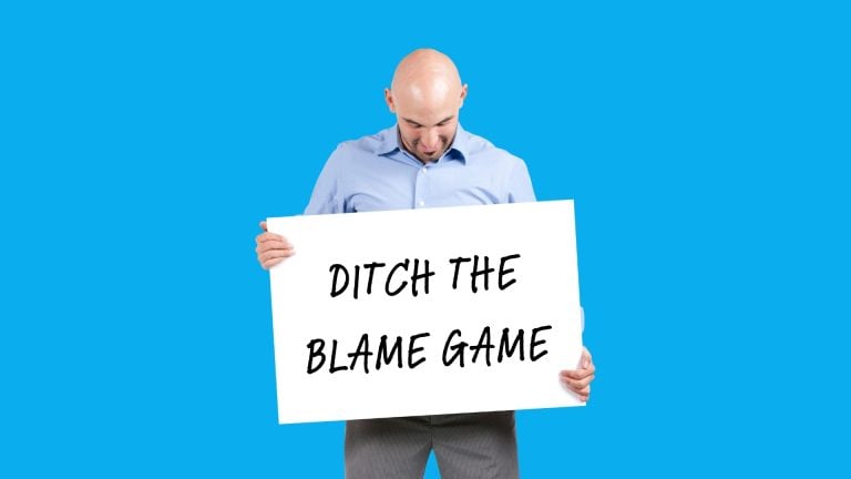 A man holding a sign that says "ditch the blame game"